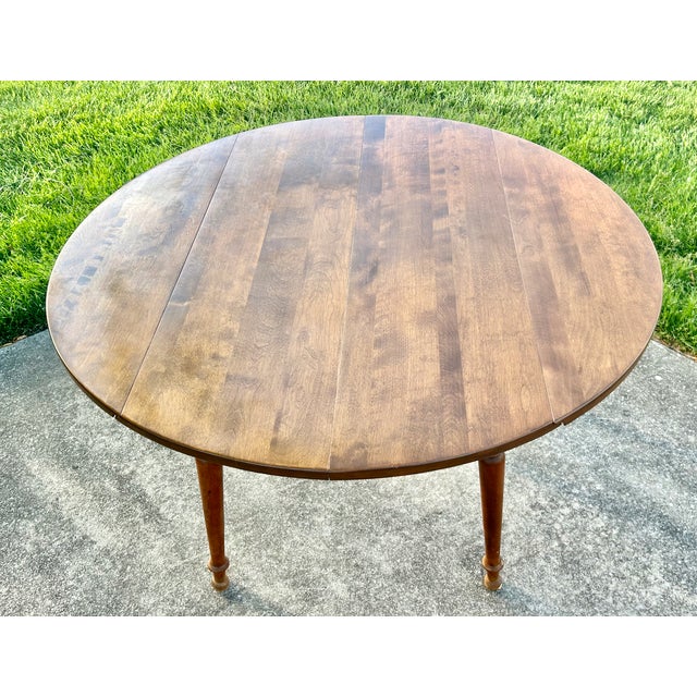 Vintage (1950's) Round Drop Leaf Table has an Americana Style. Made by Ethan Allen. The Wood is Maple. The Table's Legs...