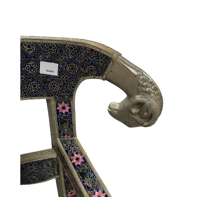 Ornate decorative bench featuring a dark enamel or cloisonné-style patterned frame with raised floral and geometric...