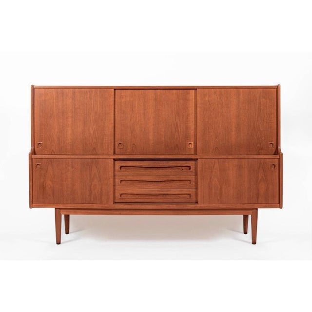 This vintage mid-century Danish modern tall teak wood sideboard server or bar cabinet attributed to Johannes Andersen for...