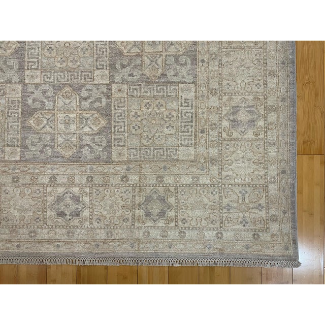 This handmade Chobi rug from Afghanistan features a refined geometric pattern composed of soft beige, stone, ivory, and...