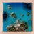 This artwork presents an aerial view of an ocean landscape, where vibrant shades of blue intermingle with textured...