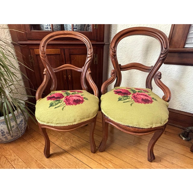 This pair of 19th century antique Victorian mahogany balloon back parlor side chairs have original floral needlepoints,...