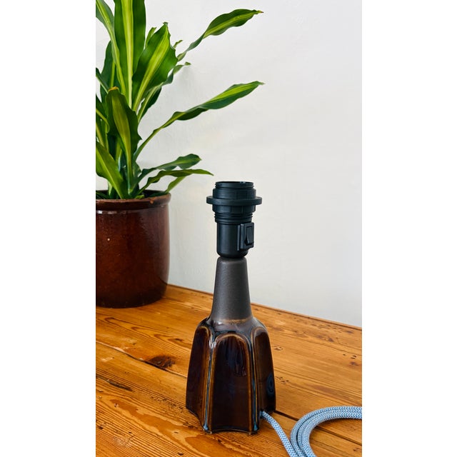 Ceramic table lamp with a hexagonal base, decorated with blue and brown glazed tones and featuring an unglazed neck....
