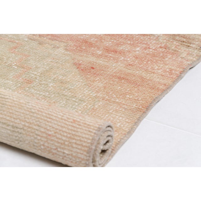 This is a vintage Turkish Oushak rug from the Mid 20th Century. The piece was hand-knotted.