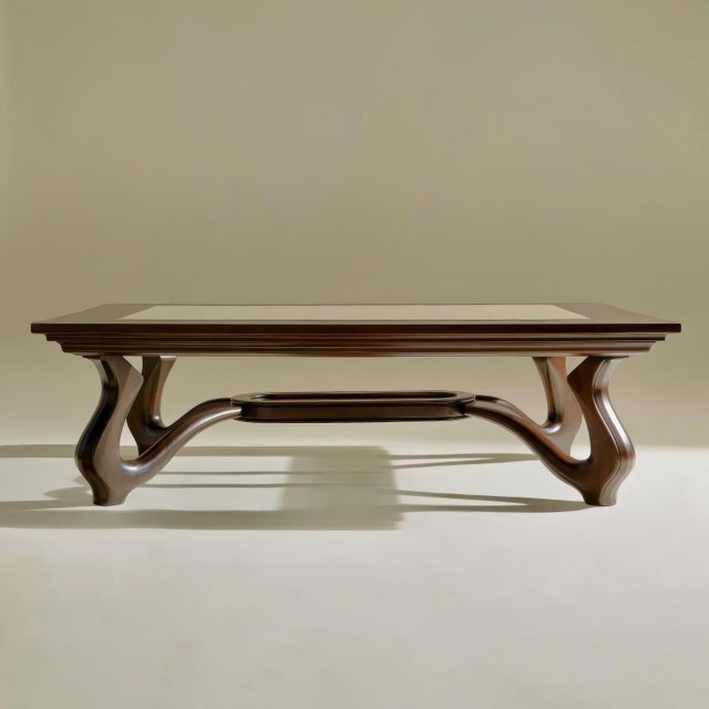 A striking contemporary sculptural coffee or center table featuring a richly stained walnut form with an inset glass top,...