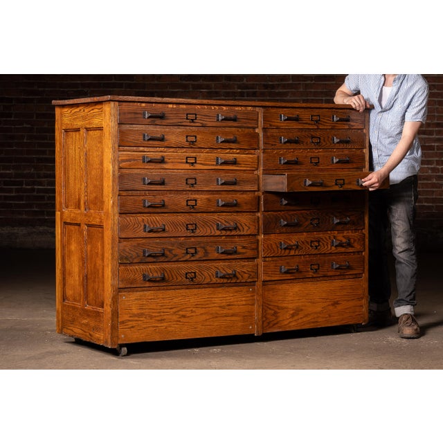 Large quarter-sawn oak flat file cabinet with sixteen shallow drawers arranged in two vertical banks, retaining dark...
