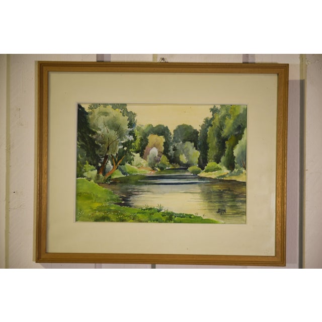 Watercolor signed J. Richard, dated 1975, depicting a tree-lined river in a peaceful countryside landscape. Beautiful soft...