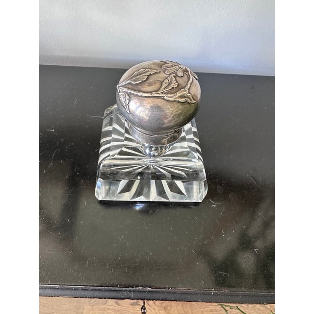 This is a late 19th century crystal and sterling hinge topped inkwell. The silver top has a floral repoussee design and...
