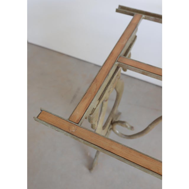 An elegant and sculptural mid 20th century dining or center table featuring a cast-iron base with graceful swan-neck...