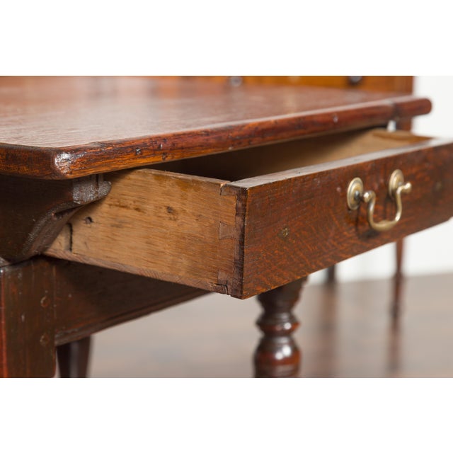 An English Georgian period oak side table from the early 19th century, with single drawer, turned legs and stretchers....