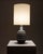 A table lamp representative of European design from the 1960s and 70s, crafted from glazed ceramic with a matte black...