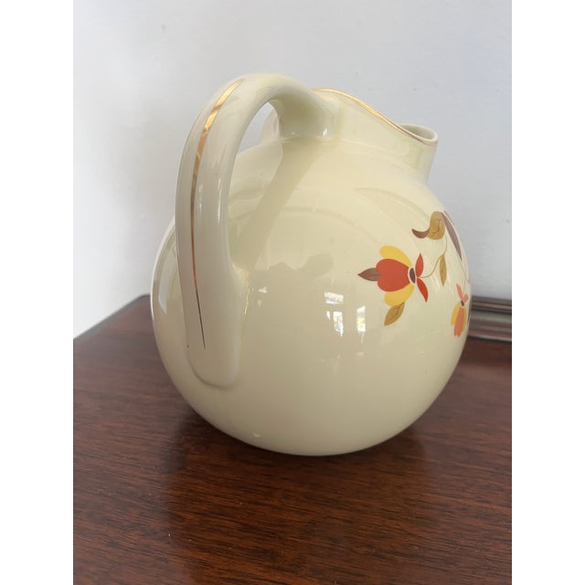 A generously scaled vintage Hall China pitcher in the iconic Jewel Tea Autumn Leaf pattern. The softly ribbed ivory...