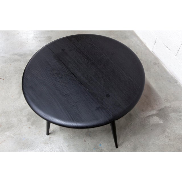 Ercol coffee table, 1960s model 308, with a matte black half-moon top. Diameter 61cm. Designed by Lucian Ercolani, this...