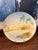 Featuring a sunset landscape with palm trees in soft pastel tones, finished with a gilt rim. Backstamped “Hand Painted...