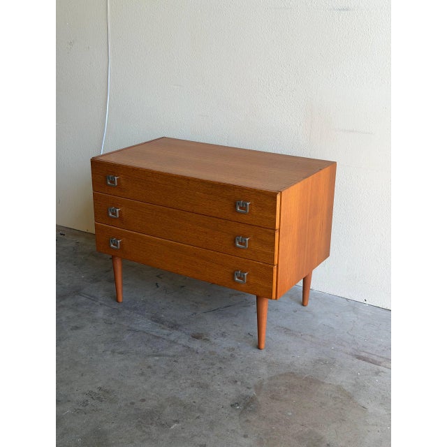 Danish chest of drawers crafted in warm teak wood. This compact yet functional piece features three spacious drawers with...