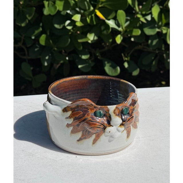 Vintage ceramic cat bowl featuring a sculpted cat face with expressive features and striking turquoise-green eyes. The...