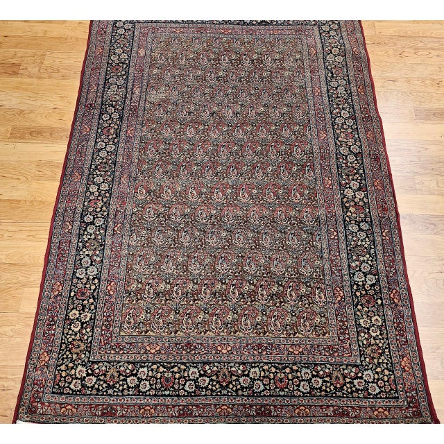 "A finely hand-knotted vintage Persian Qum area rug from the early 1900s featuring an exquisite allover paisley pattern on...
