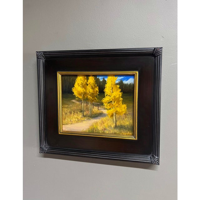 This oil painting captures a serene pathway lined with vibrant golden aspens, their striking yellow leaves contrasting...
