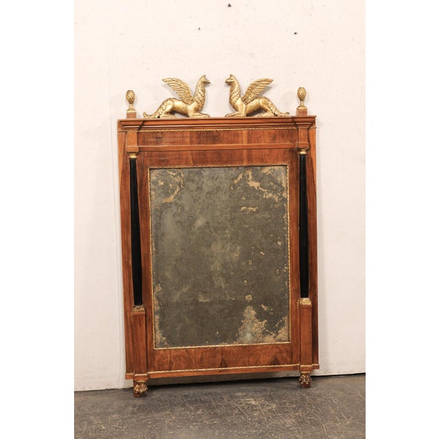 A French decorative mirror, with griffin crest and paw feet, from the early 19th century. This antique mirror from France,...