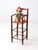 Charming antique child’s high chair crafted with a tall wooden frame, slender stretchers, open arms, and a woven seat. The...