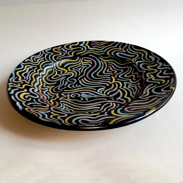 This large centrepiece comes with a stylized decoration on a black iridescent background. It is signed Deruta.