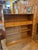 Mid-Century Modern Style Bookcase featuring an upper shelf, two drawers with round wooden knobs, and lower sliding glass...