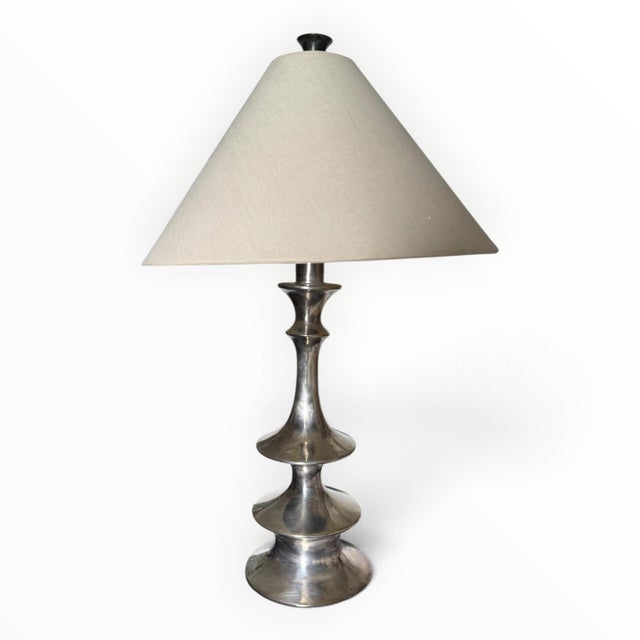 A pair of beautiful sculptural table lamps with a patinated silver finish. White linen conical shades and matching...