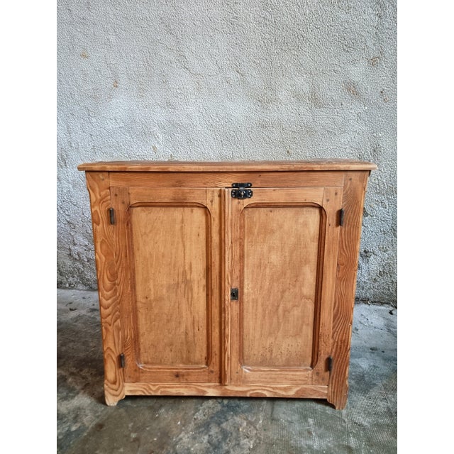 This antique French pine cupboard dates from the early 20th century and is crafted from pine wood. The cabinet features...