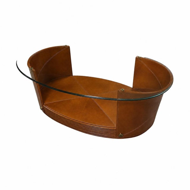 Bring a sophisticated touch of equestrian-inspired modernism to your living space with this striking oval coffee table....