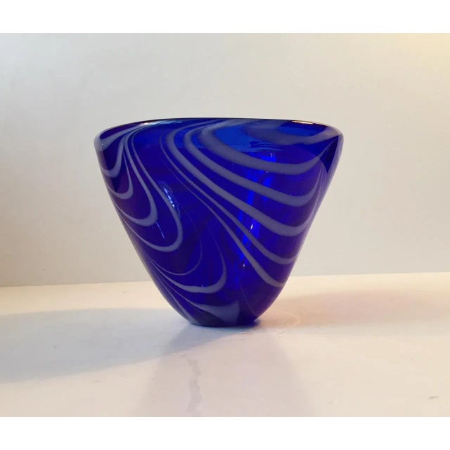 This thick cobalt blue conical glass bowl has a white spiral decoration and is made of opaque glass. It was manufactured...
