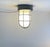 A cage flush mount ceiling or wall light in opaline glass and black painted metal. Great industrial or even submarine vibe...