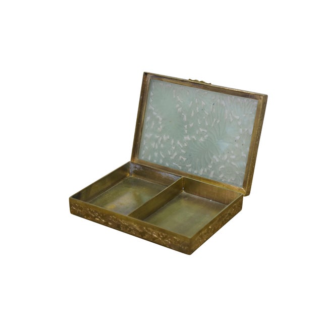 Mid to early 20th century Chinese lidded box features an intricately carved jade top set into a solid, etched brass base....