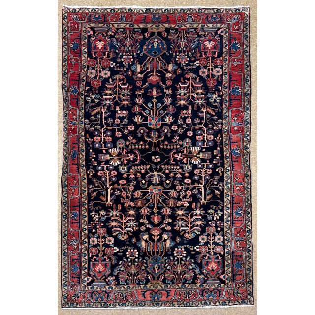 Antique hand-knotted rug from the Nahavand region of western Iran, featuring a detailed tree-of-life design on a deep navy...
