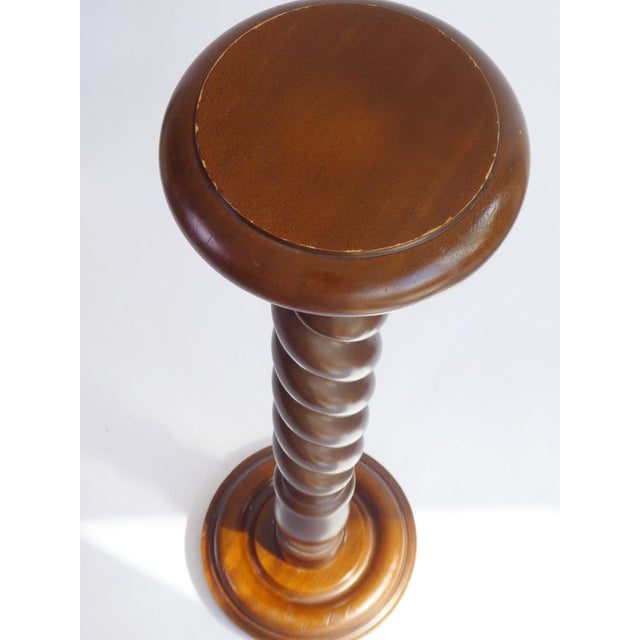 A tall vintage wooden pedestal with a barley twist column. It has a round top and a carved base. Beautiful pedestal/side...