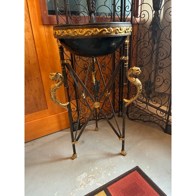 Jardinière plant stand or decorative piece in the neoclassical Egyptian revival style has an iron tripod frame with X-form...