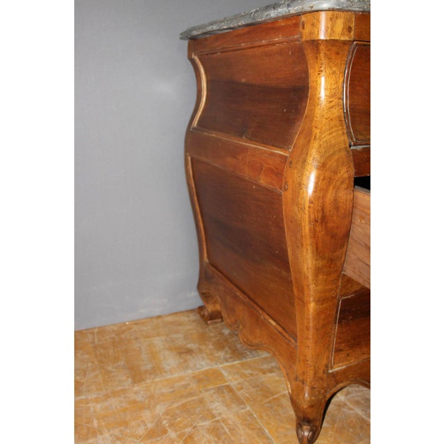 A solid walnut commode, known as a "Tombeau" commode, with three drawers, curved on three sides, scrolled feet, and an...