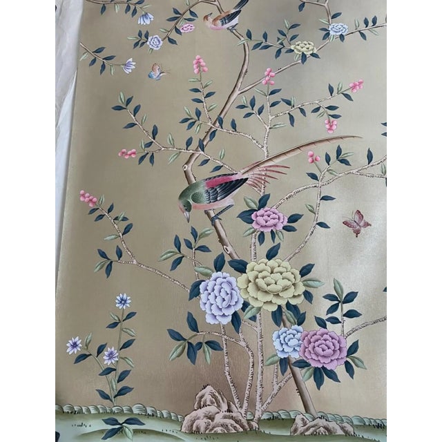 A sophisticated hand painted champagne silver wallpaper featuring delicate birds, blooming flowers, and graceful botanical...