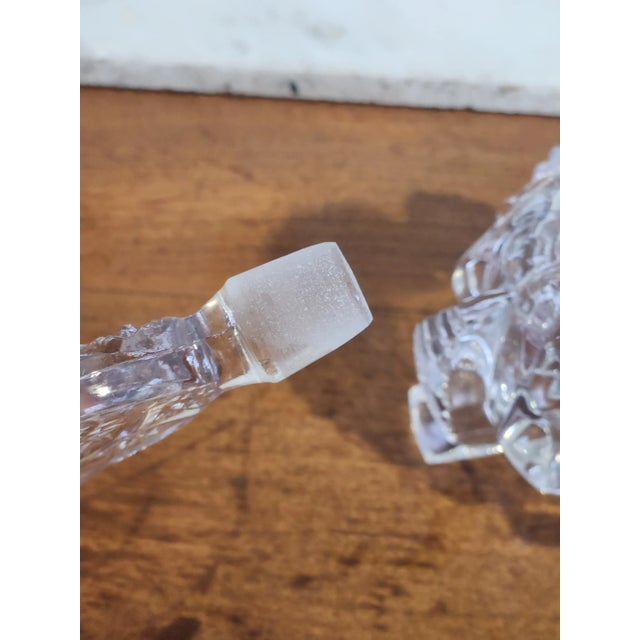 This is a clear glass perfume bottle with a tall open design, cut stopper. The bottle and stopper have different designs,...