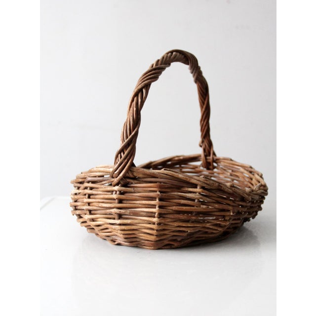 This vintage handmade wicker basket features a softly twisted handle and an open, irregular weave that adds warmth and...