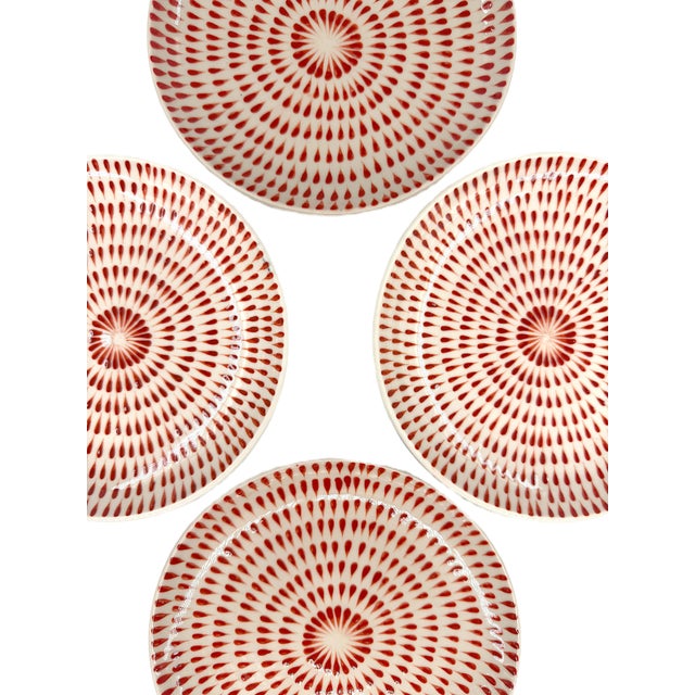 A striking set of four Bat Trang ceramic dessert plates featuring a rhythmic, radiating pattern in rich red against a warm...
