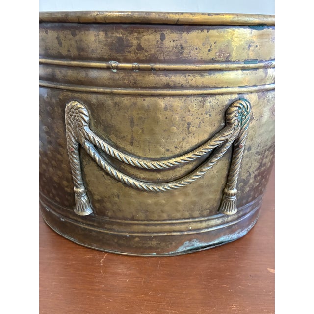 Vintage brass tone oval planter/cachepot featuring elegant rope swag embellishments and a beautifully aged patina. This...