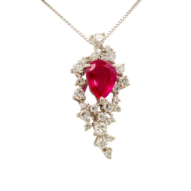 A striking pendant necklace featuring a vibrant pear-cut ruby as its centerpiece. The ruby, weighing 2.11 carats, radiates...