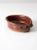Vintage handmade studio pottery bowl with a rich reddish-brown glaze and subtle speckled undertones. The small oval form...