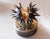 A contemporary still-life bronze of a chestnut splitting open in its spiny husk, the bristling case parting to reveal the...