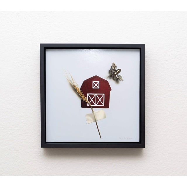 This artwork features a striking red barn silhouette accompanied by a delicate wheat stalk and a detailed bee, all set...