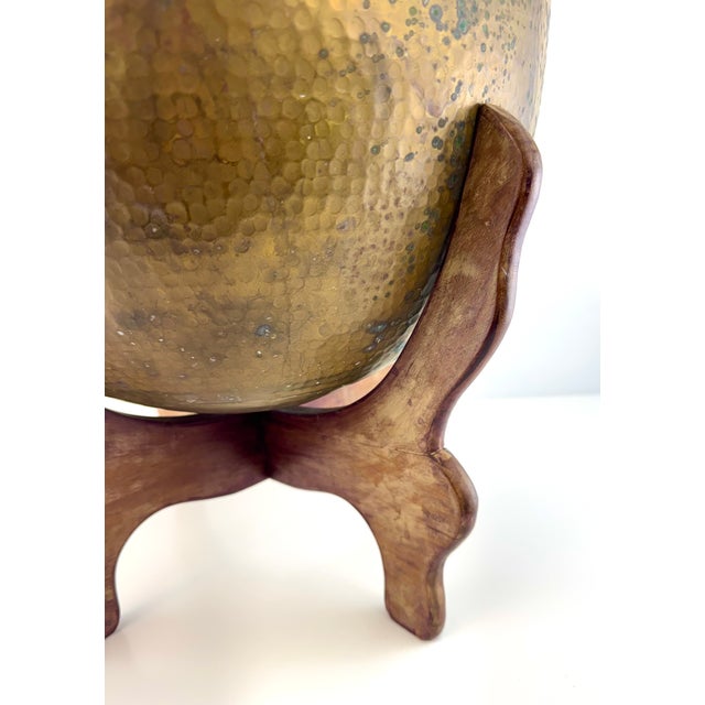 Crafted from richly patinated hammered brass, this vintage jardiniere is paired with its original carved wooden stand for...