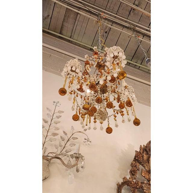This listing features a champagne, orange, and clear crystal chandelier that most likely originated from France in the...