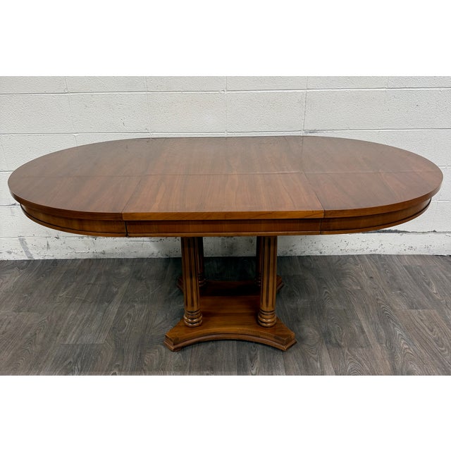 This is a vintage Neoclassical Regency Revival walnut pedestal dining table featuring a beautifully figured walnut veneer...