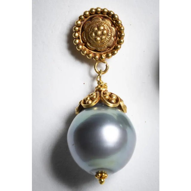A pair of classically different pearl drop earrings. These feature fine hand-tooling on the earring stud and gold end cap...