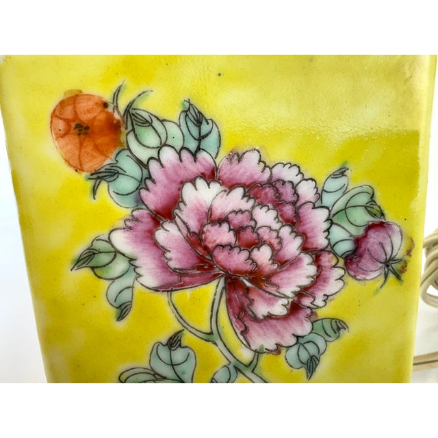 A vibrant vintage porcelain table lamp featuring a richly saturated yellow ground adorned with delicate hand-painted...